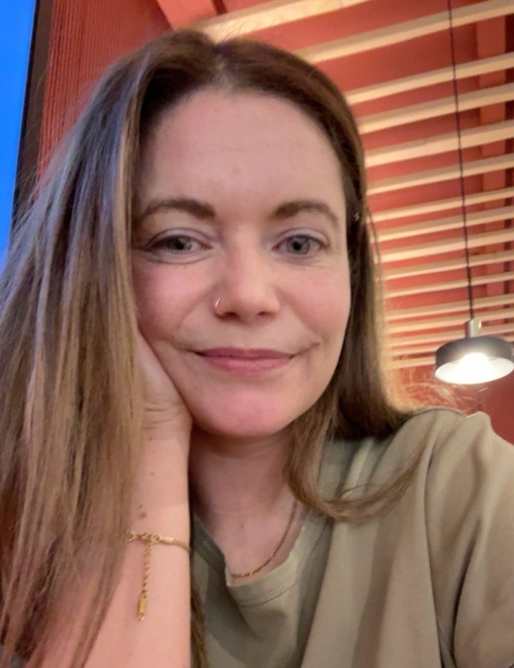 Elaine, smiling with her hand against her cheek